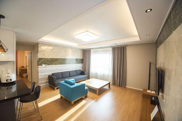 A modern living room with a sofa, coffee table, and TV stand. - Eunbille (Seogwipo)
