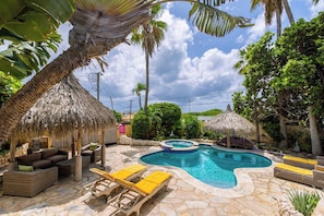 A pool area with lounge chairs, a hot tub, and thatched umbrellas. - Tropical Haven! 5BR w/ Lush Pool Backyard Retreat (Ponton)