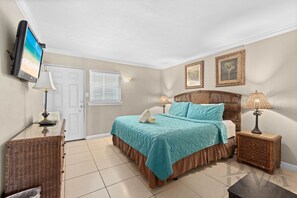 A bedroom with a bed, a television, a door, and a window. - Gulffront w/ Balcony & Kitchen – Silver Sands #253 by RVA (Longboat Key)