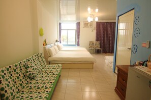 Un dormitorio con una cama doble, un sofá verde, un aparador y vistas al exterior.