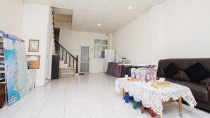 A spacious living room with a staircase, a dining table with a lace tablecloth, and a brown leather sofa.