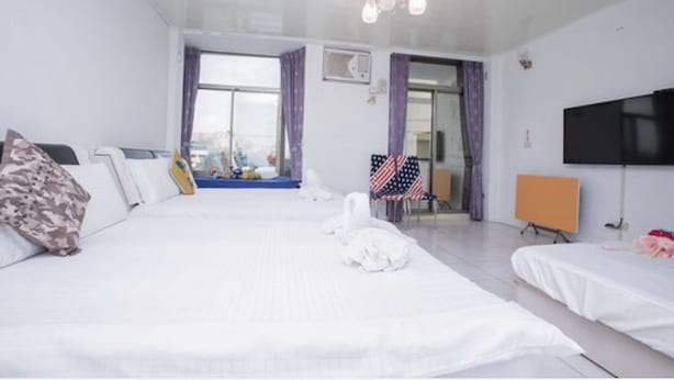 A hotel room with a large bed, a TV, and a view of the city.