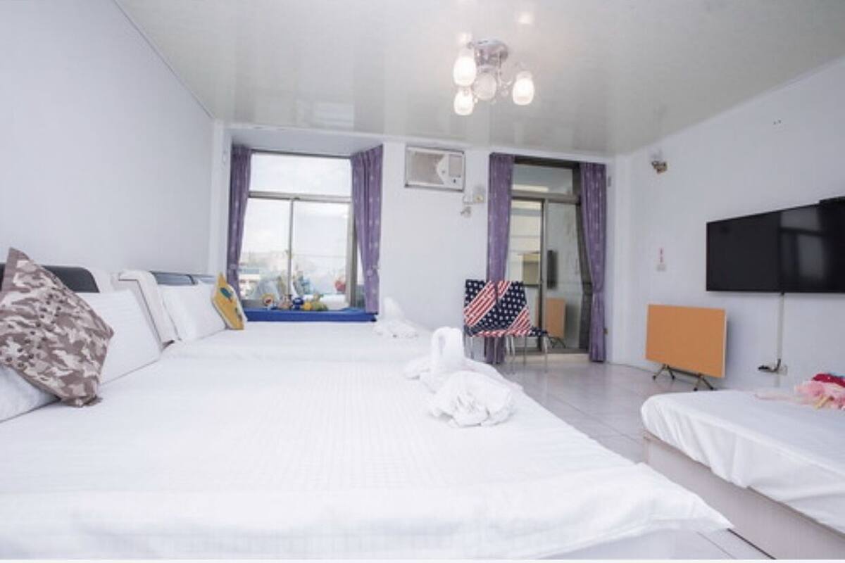 A hotel room with a large bed, a TV, and a view of the city.