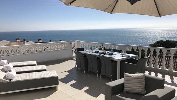 A terrace with a table set for dining, lounge chairs, and a view of the sea. - Stunning Detached 3 Bedroom Villa with Private Pool and Sea View  (Peñíscola)