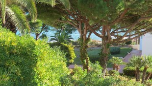 A lush garden with various trees and shrubs, a paved pathway, and a view of the sea. - Stunning Detached 3 Bedroom Villa with Private Pool and Sea View  (Peñíscola)
