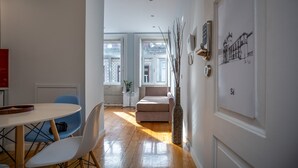Una sala moderna con un sofá, una mesa de comedor con sillas y un florero.