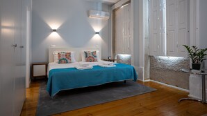 Un dormitorio con una cama, dos lámparas de pared, aire acondicionado y una planta en maceta.