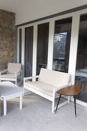 A modern outdoor seating area with a sofa and chairs, a small table, and a stone wall.