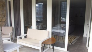 Une pièce moderne comprenant un canapé, des fauteuils, une petite table et une porte-fenêtre coulissante donnant sur un balcon.