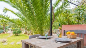 A wooden table set outdoors with a glass, a bottle, and a basket of fruit. - CAN PINA - ECO REDONDA 2 - Apartment with shared pool in Costitx. Free WiFi (Costitx)