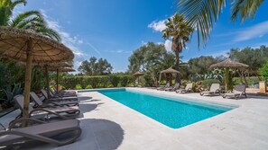 A poolside area with lounge chairs and thatched umbrellas, surrounded by palm trees and greenery. - CAN PINA - ECO REDONDA 2 - Apartment with shared pool in Costitx. Free WiFi (Costitx)