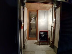 A narrow hallway leading to a room with a wooden door and a sign reading "OSAKA HOSTEL". - OSAKA HOSTEL kai (Osaka)