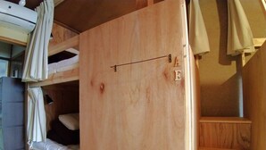 Una cama litera de madera con un estante pequeño y una cortina.