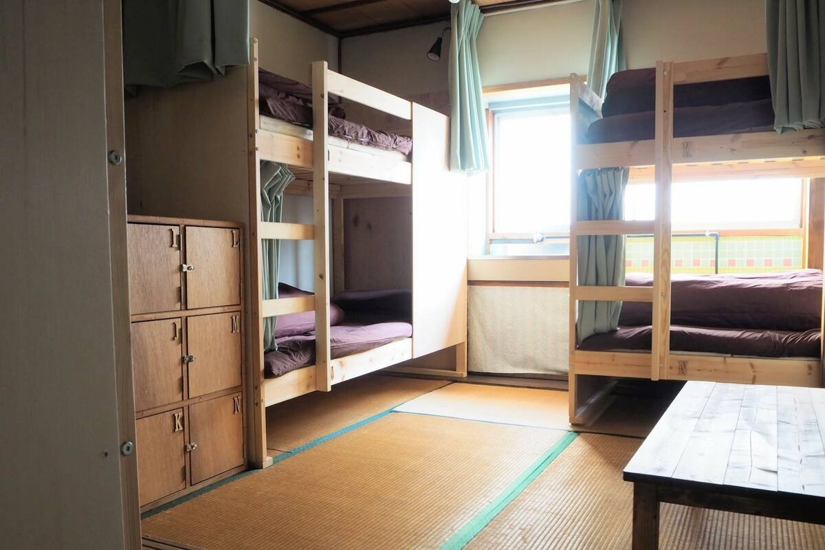 Un dormitorio con literas, un armario de madera y una ventana con cortinas.
