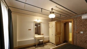 A bedroom with a bed, a dresser, a mirror, and a door leading to another room.