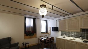 A modern kitchen with a dining area, a black sofa, and a chandelier.