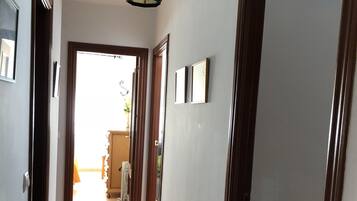 A hallway with a tiled floor, wooden doors, and a hanging light fixture.