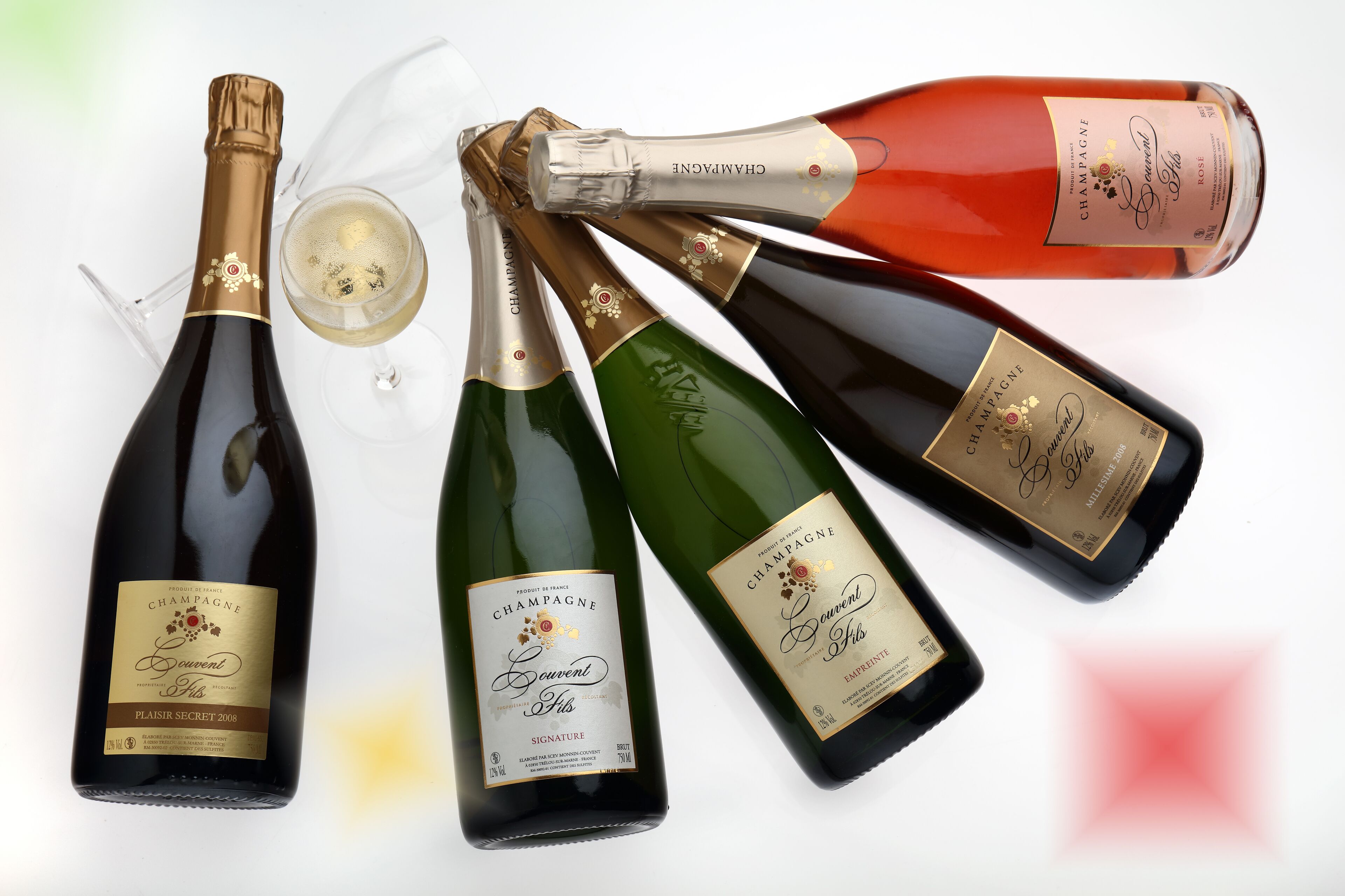 Eine Auswahl an Champagnerflaschen mit Etiketten, eine davon ist geöffnet und enthält ein teilweise gefülltes Glas.