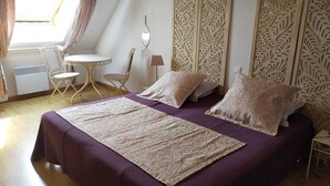 A bedroom with a bed, two chairs, a small table, and a decorative panel. - country holiday home - in Champagne - Trélou sur Marne (Trélou-Sur-Marne)