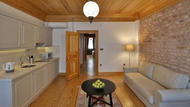 Eine moderne Küche mit Holzboden, ein Essbereich mit rundem Tisch und eine Sitzecke mit einer Couch.