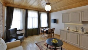Ein modernes Wohnzimmer mit einer Couch, einem Esstisch mit Stühlen, einer Küchenzeile mit Schränken und einem Fernseher.