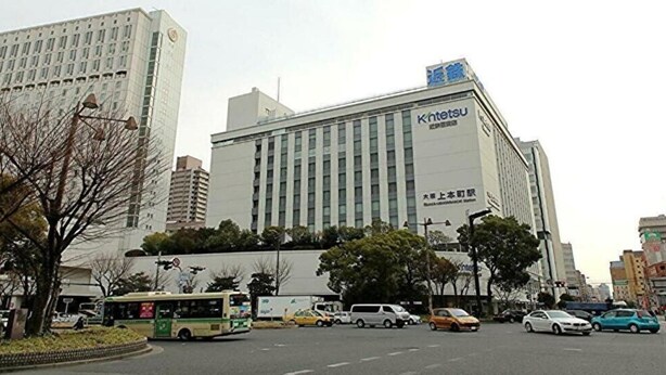 A multi-story building with signage for Kintesu and a large parking lot in front. - Hotel Axia Inn Osaka Uehonmachi (Osaka)