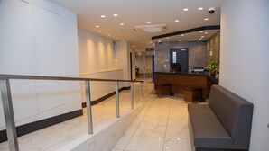 A modern lobby with a reception desk, a seating area, and a staircase with a metal railing. - Hotel Axia Inn Osaka Uehonmachi (Osaka)