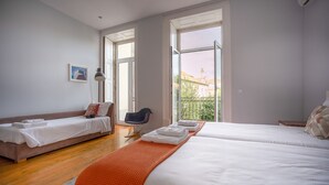 Ein Hotelzimmer mit zwei Betten, einem Schlafsofa, einem Sessel und einem großen Fenster.