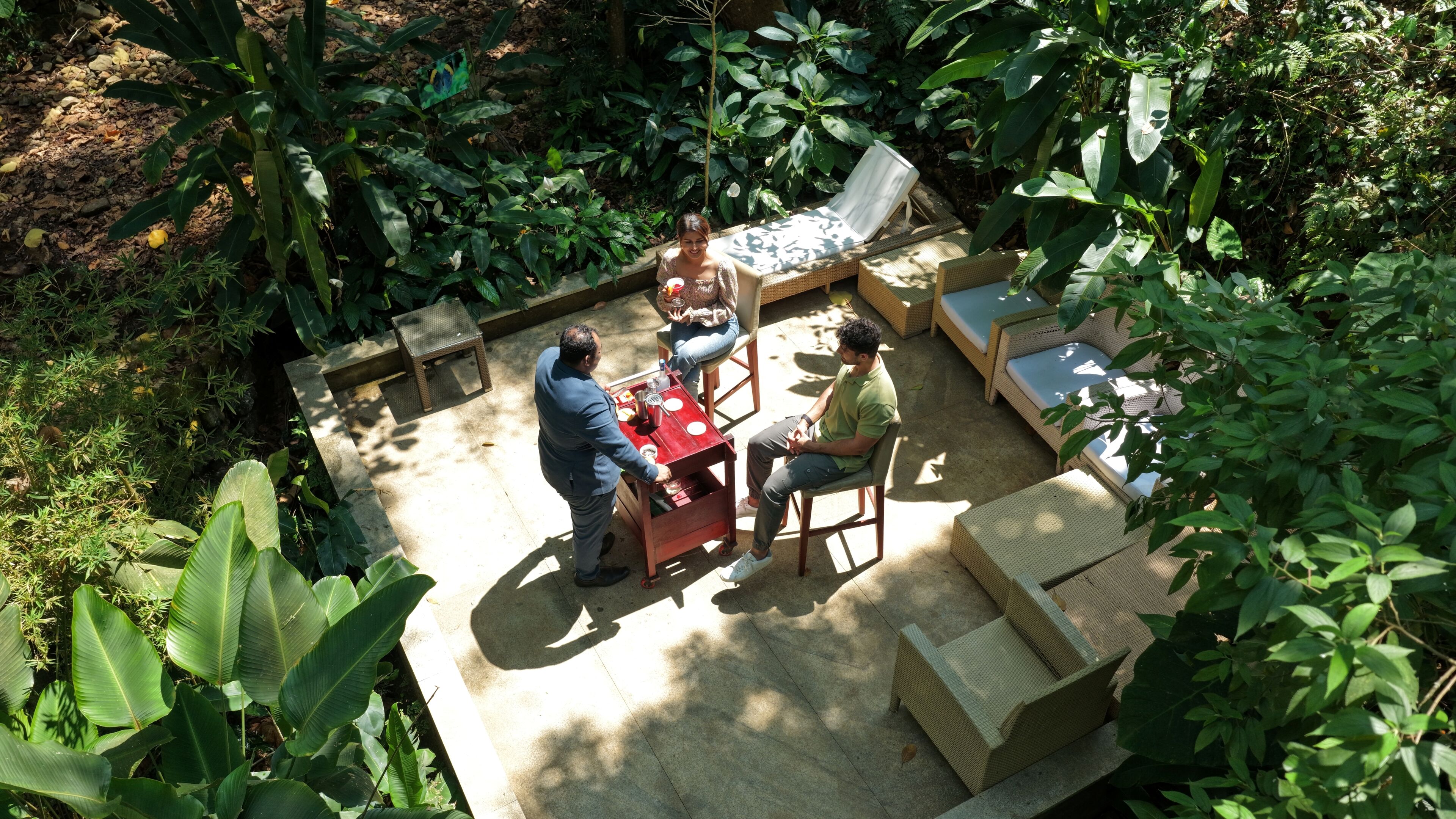 Uma área externa com mobiliário de vime, uma mesa pequena e uma cadeira.