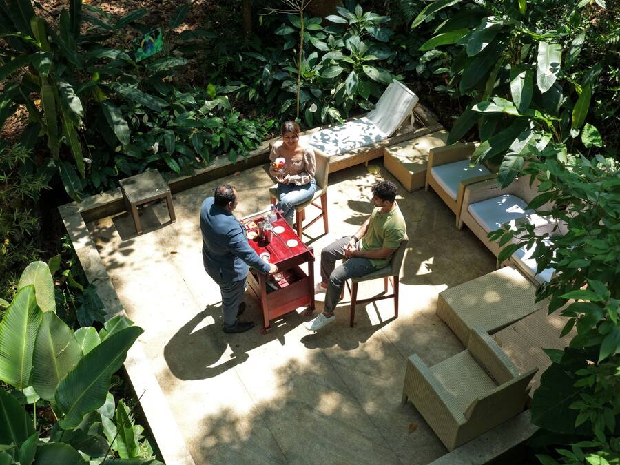 Uma área externa com mobiliário de vime, uma mesa pequena e uma cadeira.