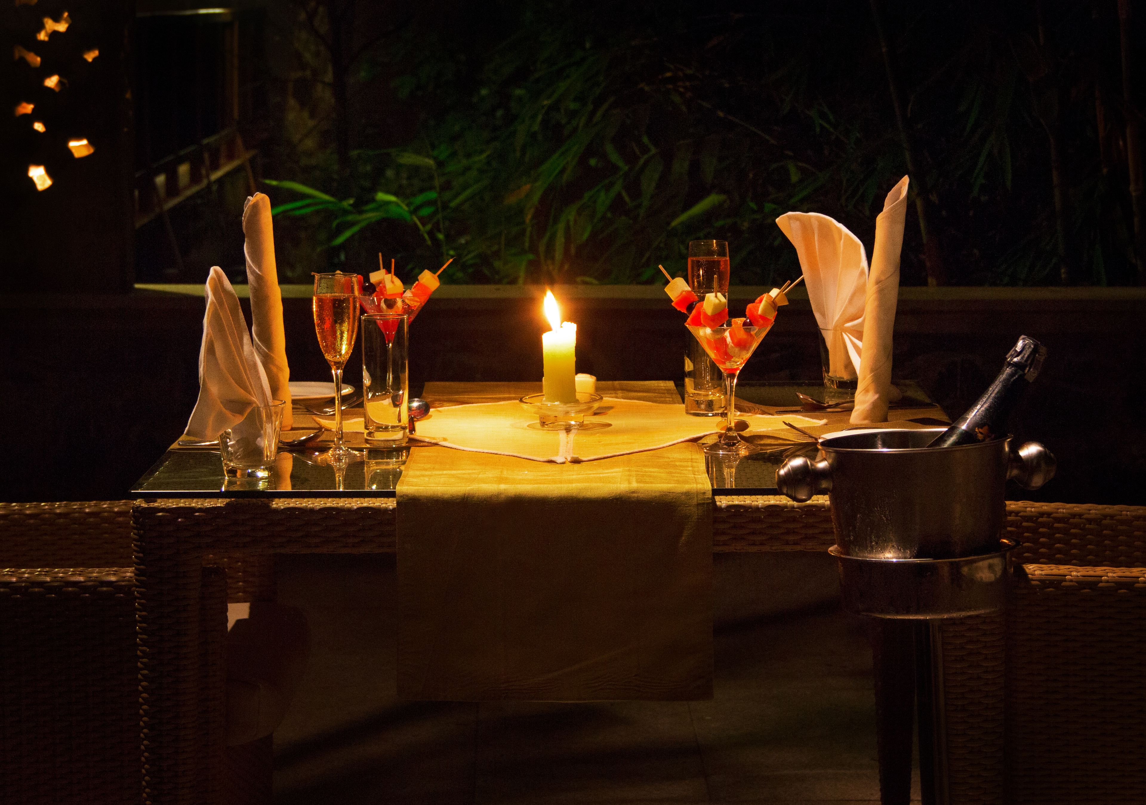 A table set for dining with a candle, glasses, and a bottle of champagne.