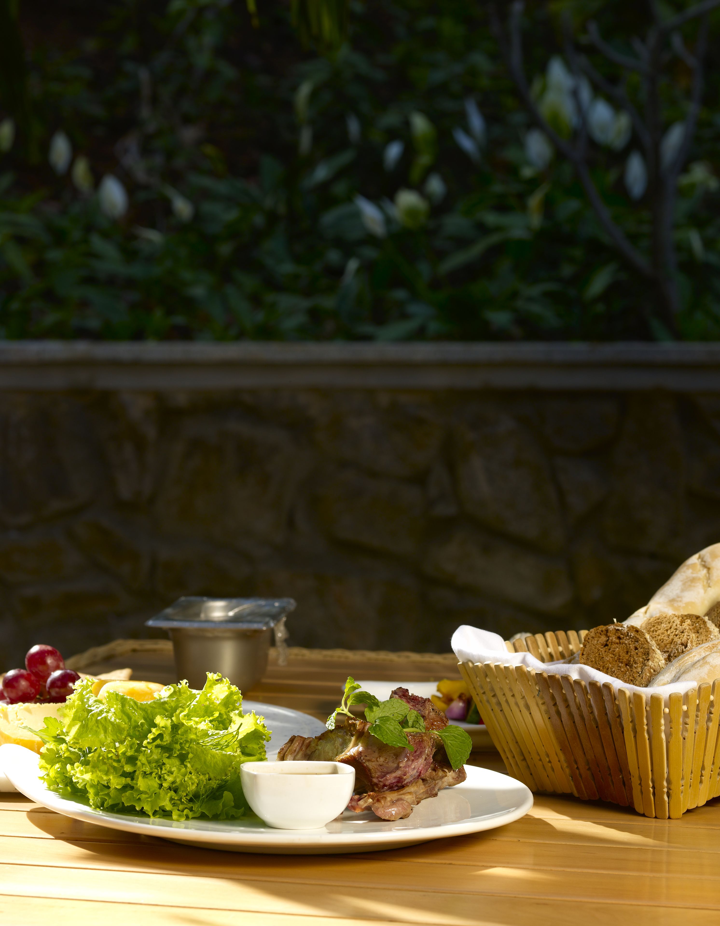 A table with a plate of food, a bowl, and a basket of bread.