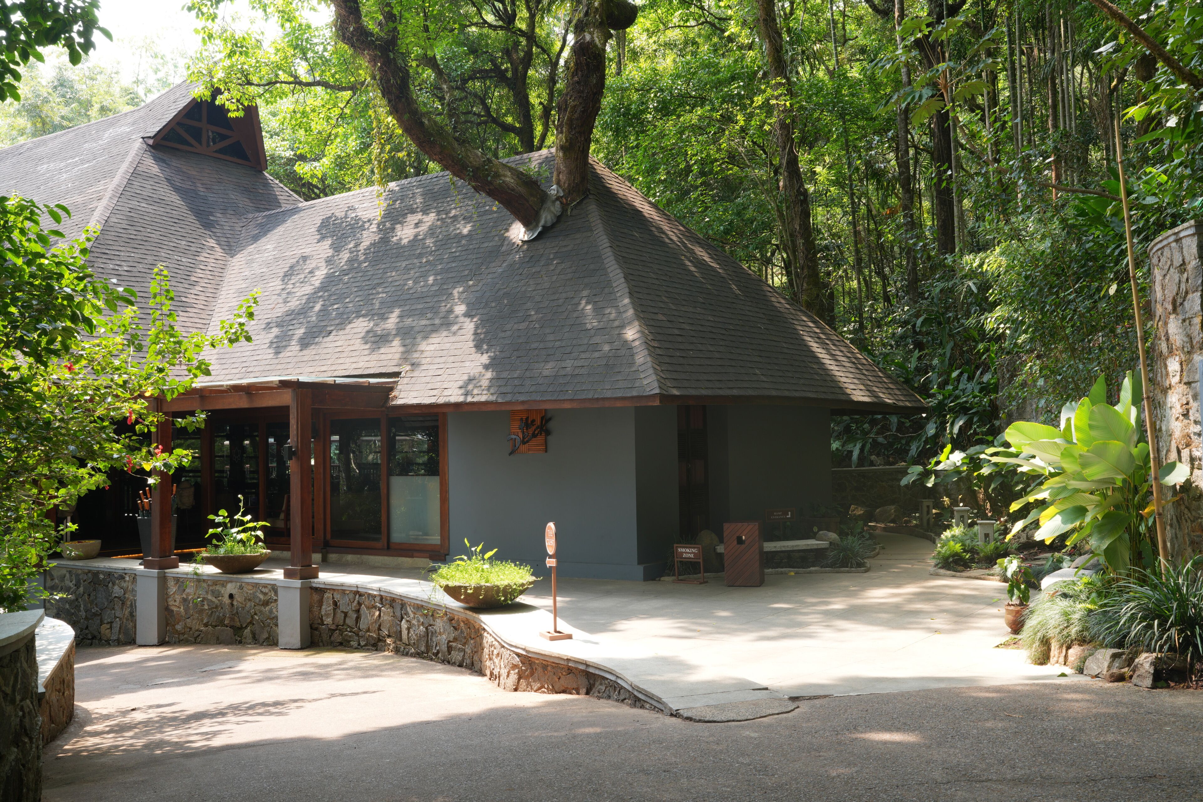 A house with a sloped roof, a stone foundation, and a paved driveway.