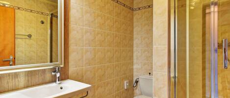 Un baño con lavabo, espejo, inodoro y cabina de ducha de vidrio.