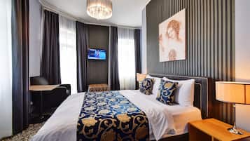 A hotel room with a large bed, a desk, a chair, a TV, and a painting on the wall.