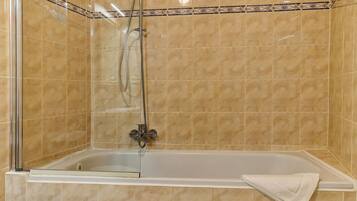 A walk-in shower with a glass door, a handheld showerhead, and a handheld showerhead.