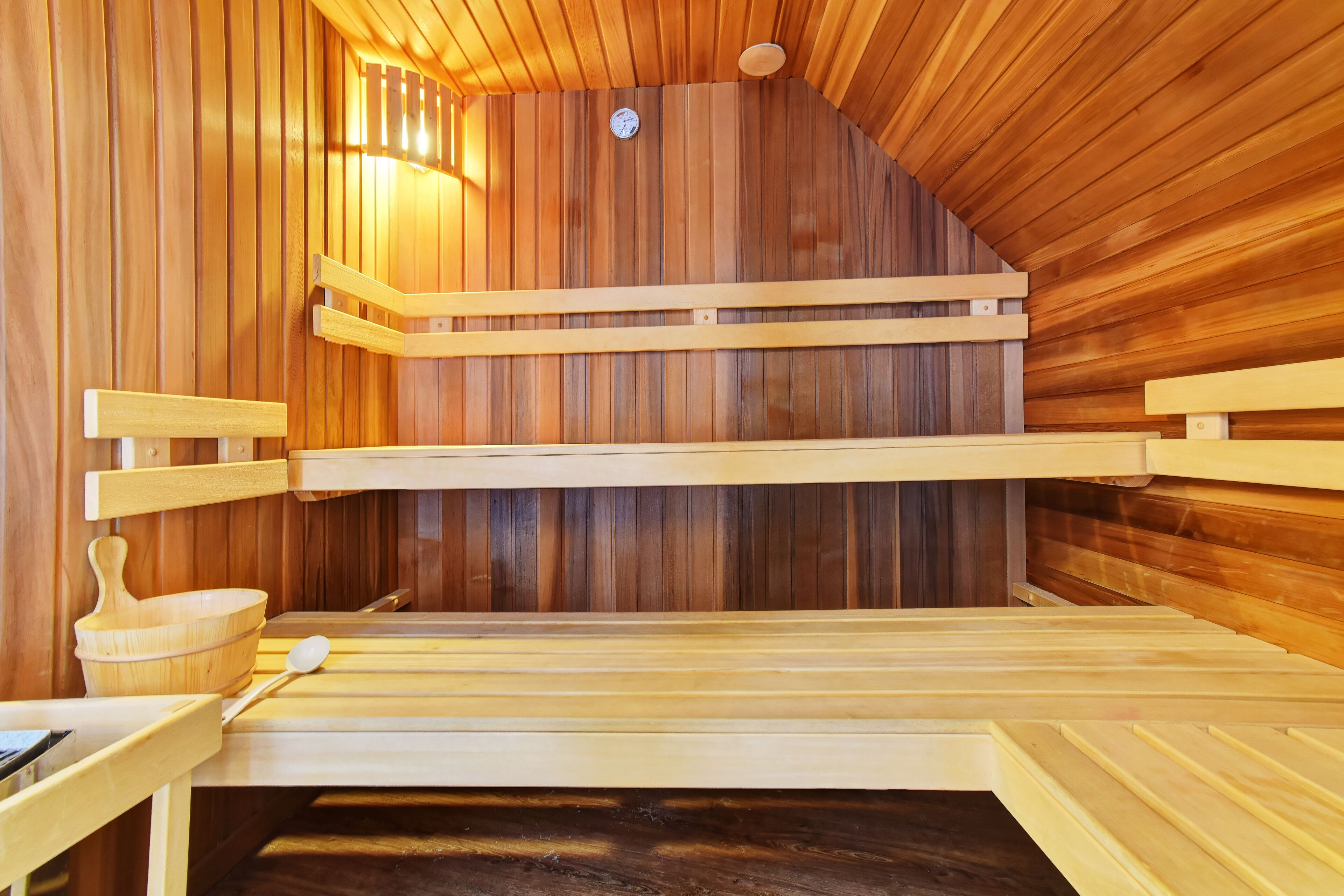 A sauna with wooden benches and a wooden bowl.