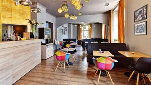 A modern restaurant with a wooden bar, colorful chairs, and pendant lighting. - Hotel DaVinci (Marianske Lazne)