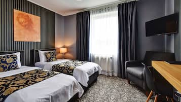 Habitación de hotel con dos camas, un escritorio, una silla, un televisor de pantalla plana y un ventanal grande con cortinas.
