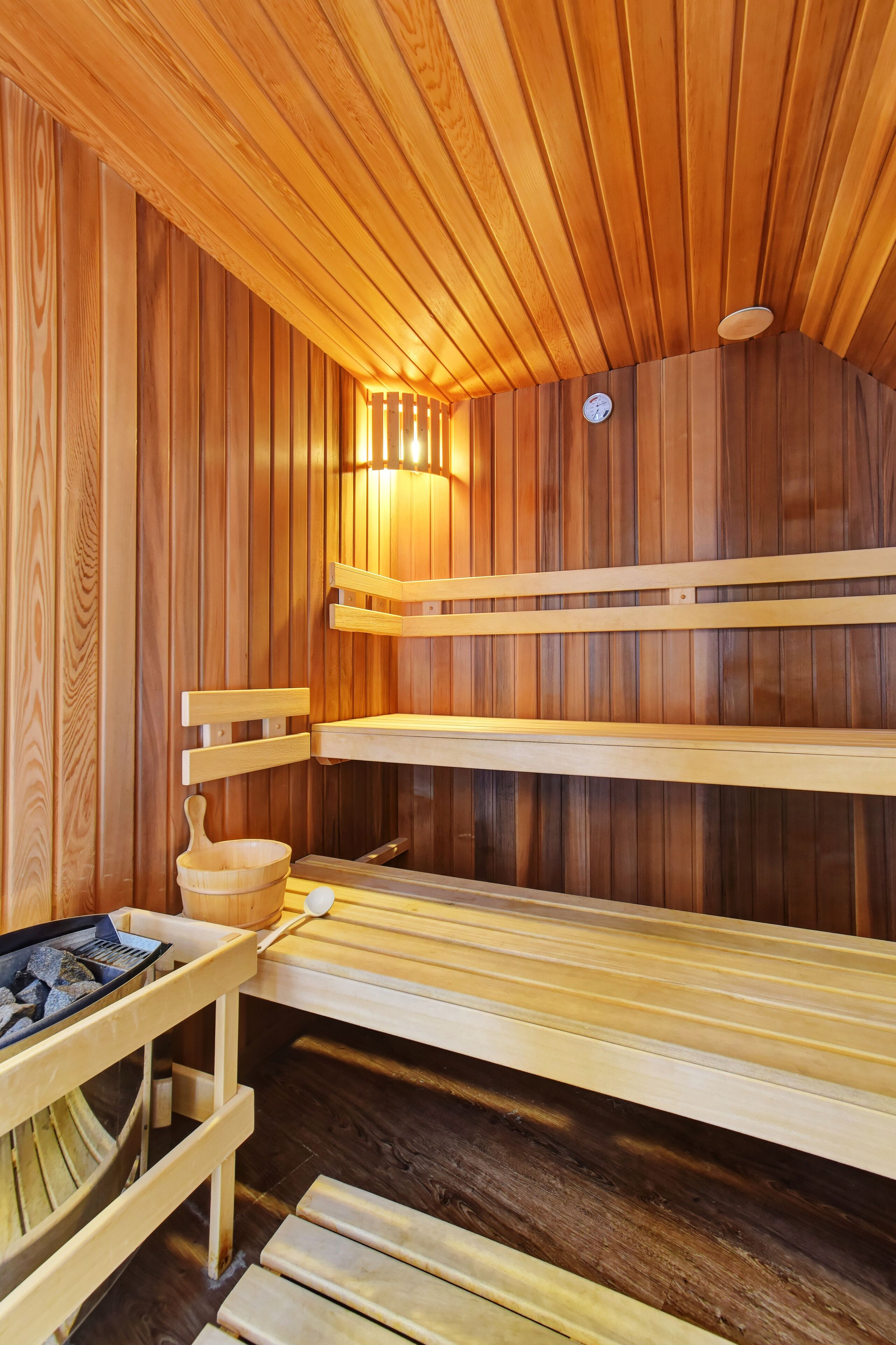 Eine Sauna mit Holzbänken und einem Holztisch mit einer Schüssel.