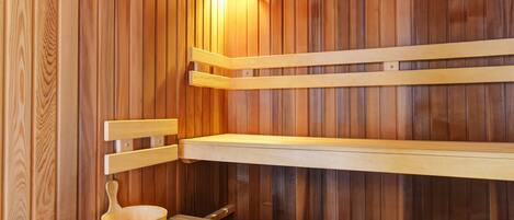 A sauna with wooden benches and a wooden table with a bowl.