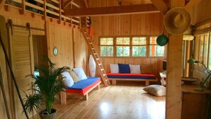 A wooden cabin interior with a loft bedroom, a dining area, and a staircase. - WOODEN HOUSE IN THE BORDER OF THE OCEAN (Soulac-Sur-Mer)