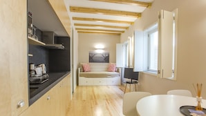 Una cucina compatta con travi in legno, un divano bianco e un angolo ristoro con tavolo e sedie.