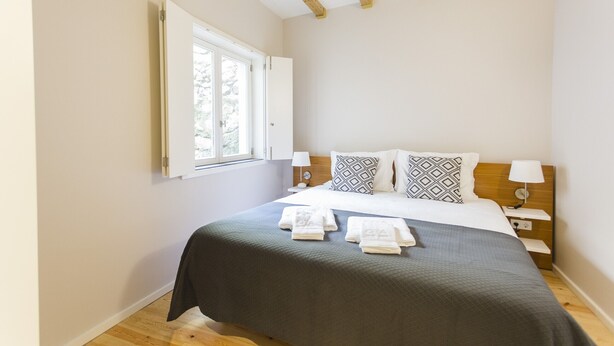 Una camera da letto con un letto, due comodini, una finestra e una trave in legno al soffitto.