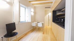 Una cucina moderna con travi in legno, un'area pranzo con sedie bianche e un piano di lavoro nero.