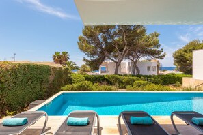 Une piscine avec des chaises longues et une vue sur un immeuble et des arbres.