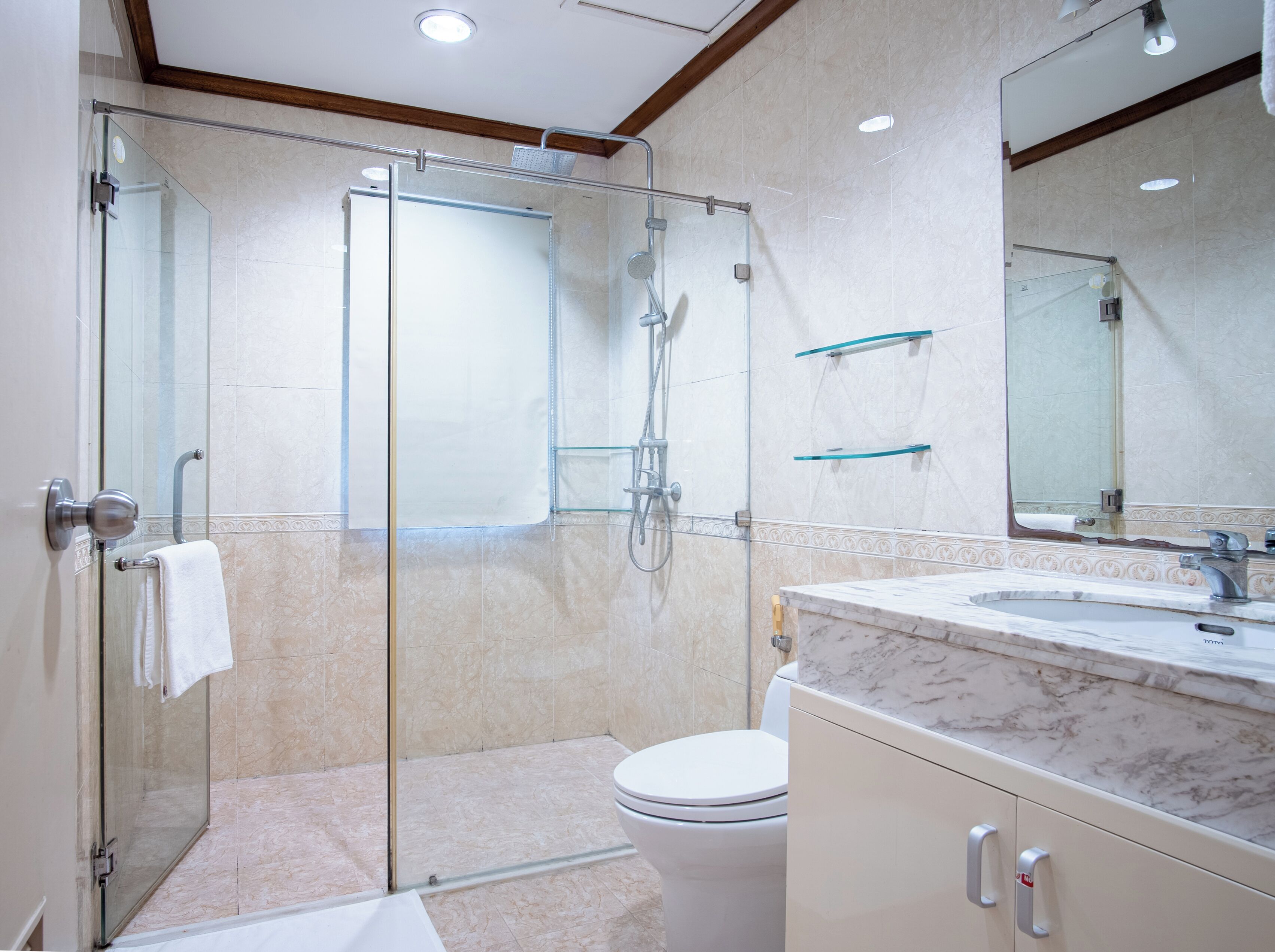 A modern bathroom with a glass-enclosed shower, a toilet, and a marble sink.