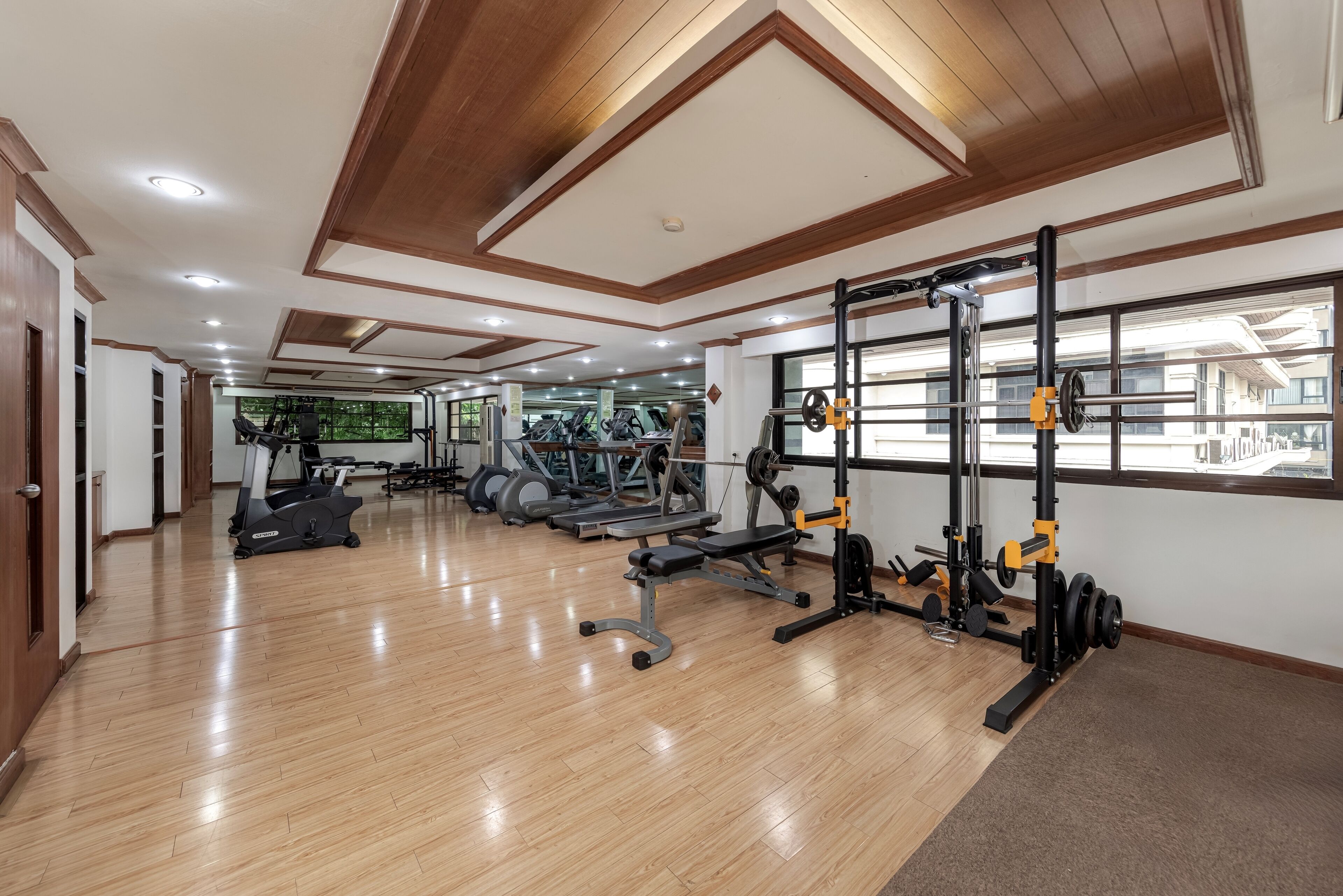 A gym with cardio machines, weightlifting equipment, and a large mirror wall.