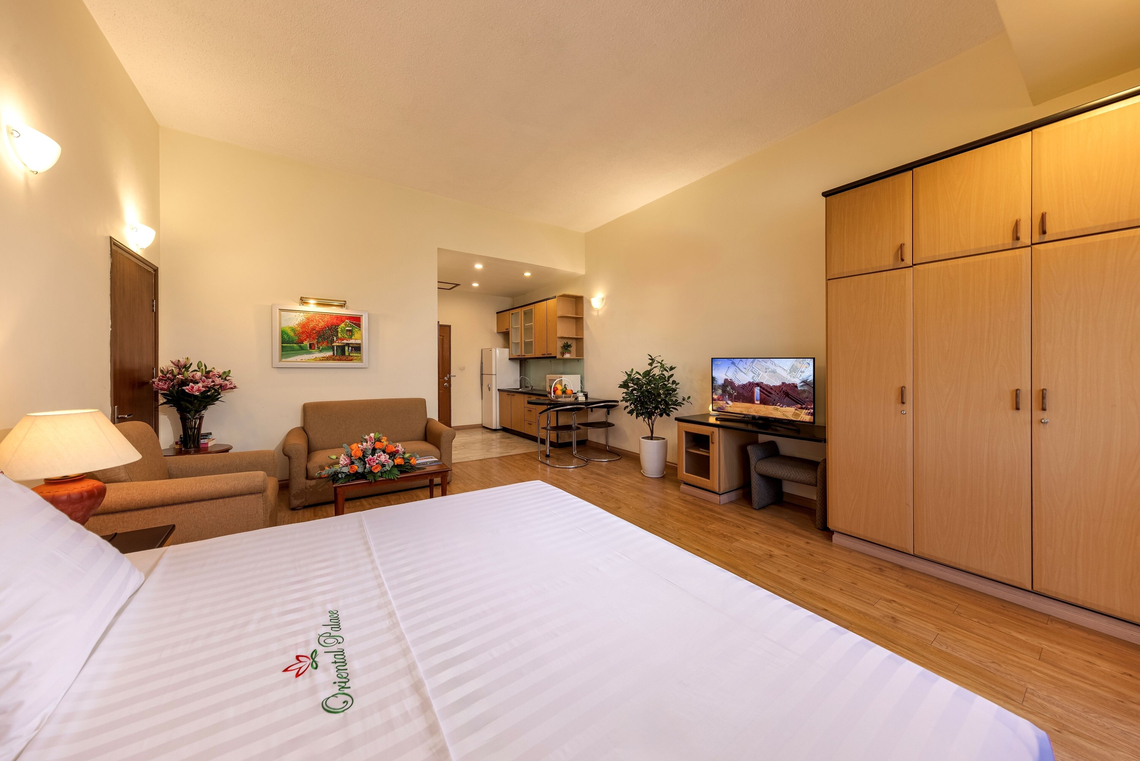 Camera d'albergo con un letto, una scrivania, una sedia, una TV, un armadio e un angolo cottura.