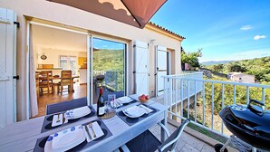 Un balcón con una mesa de comedor para dos personas, una parrilla y vistas al campo.